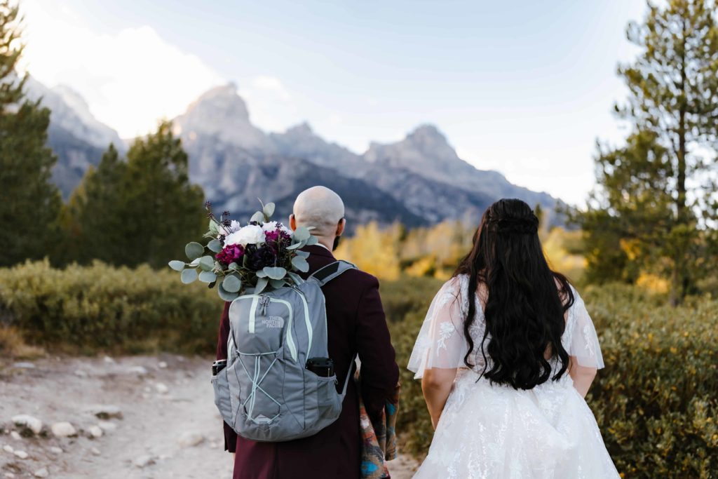 Bride and groom looking at the Grand Teton on Taggart Lake trail on their elopement day